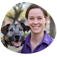 A photo of Keely, brown haired lady holding a dog and smiling
